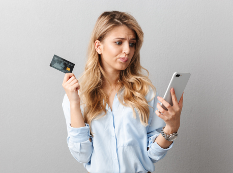 Confused person holding credit card and looking at phone