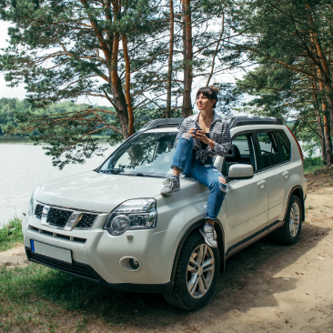 Woman sitting in woods on SUV